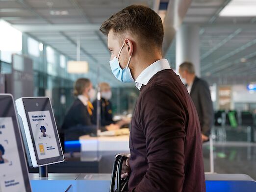 Man with mouth-nose covering at airport check-in machine