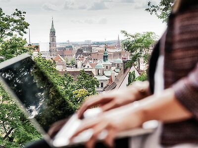 Person am Laptop, im Hintergrund ein Stadtpanorama